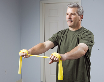 Man using resistance band to strengthen his shoulders and arms.