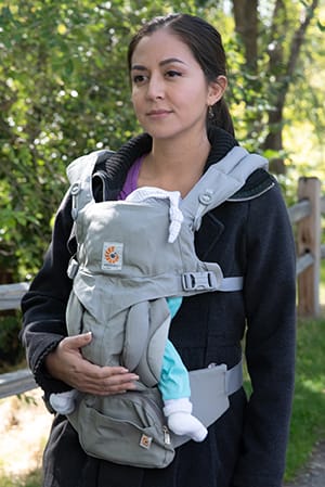 Person with baby in front carrier walking outdoors.