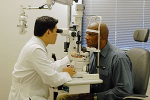 Eye doctor using machine to give person eye exam.